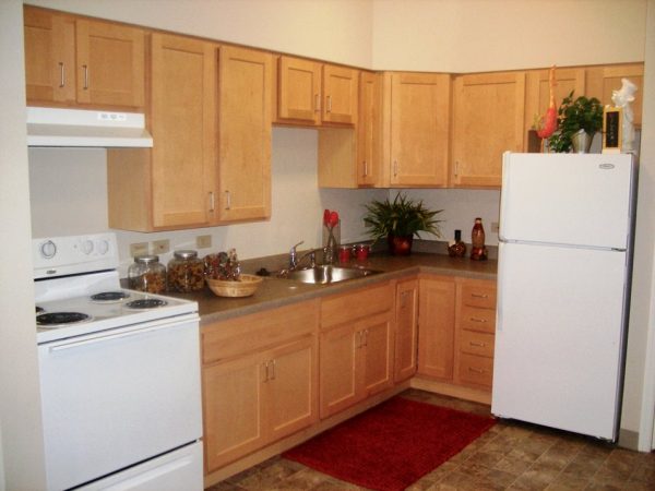 Grand South Senior Apartments model kitchen with light oak cabinets and white appliances